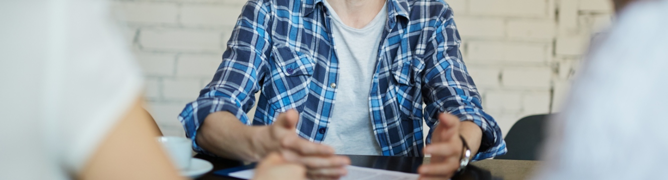 Un candidat en chemise bleue passe un entretien face à deux recruteurs 