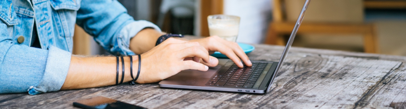 un homme écrit sur le clavier de son ordinateur portable